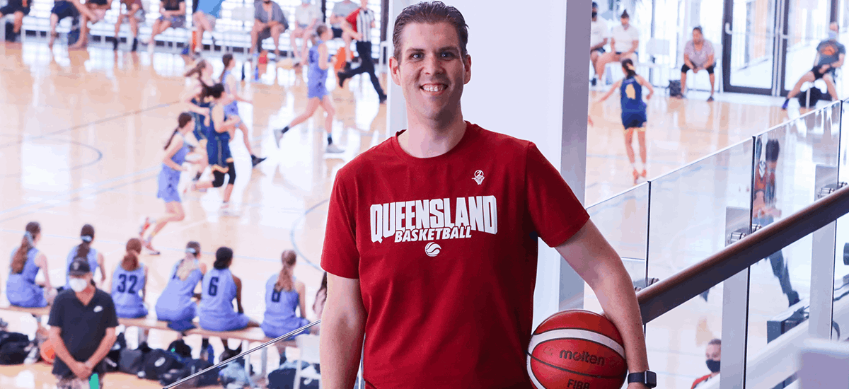 Chris Angus Stands on the viewing deck holding a Molten basketball