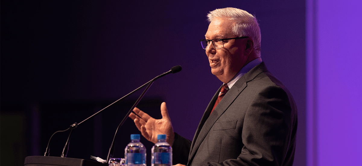 Graham Burns at podium, delivering a speech.